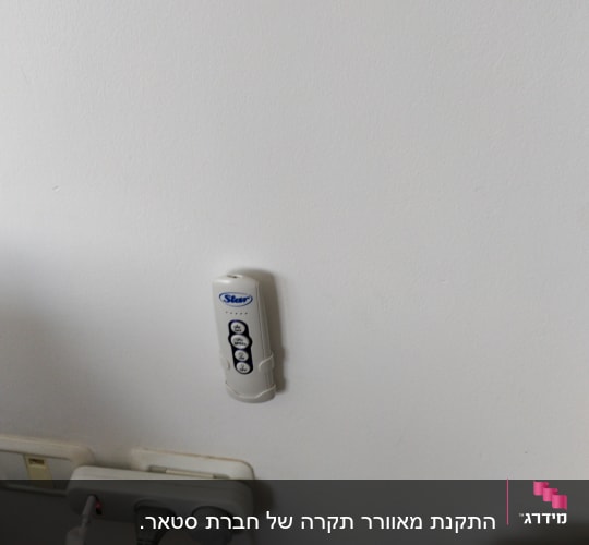 שלט רחוק על קיר ושקע חשמל עם כבלים מחוברים